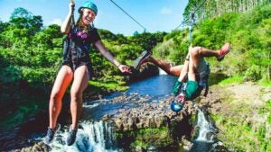 The guys and lady on the zipline at Umauma Falls are enjoying themselves.
